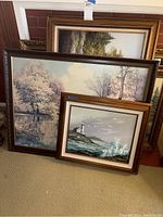 Group photo showing multiple framed prints stacked in front of a large gold framed mirror.