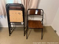 Four folding chairs stacked folded and one opened to show front profile, brown faux leather seats and backs with black metal tubular frames.