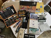 Full overview of all art supplies laid out on a table including boxes, sets, pads, and brushes