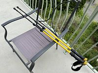 Two yellow and black adjustable trekking poles resting on a chair outdoor, showing overall length and design