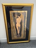 Frontal view of framed artwork showing a nude female figure from behind, 36x23 inches, gold frame with glass.