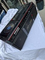 Angled side view showing the top cassette deck, control buttons, and front speaker grills with Mega-Bass logo.