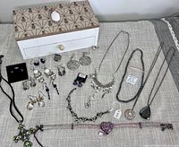 Photo of jewelry items spread out next to the wooden pineapple jewelry box showing assortment of earrings, necklaces, bracelets