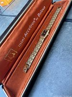 Full view of ladies Bulova watch in original orange velvet-lined mini Accutron case showing gold-tone linked bracelet and rectangular watch face.