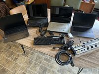 Photo showing four laptops arranged on table with keyboard and Monster power strip visible