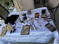 Full overview of lot items on table including gloves, hair extensions, jewelry, gloves, photograph, decorative items.