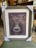 Full view of the framed artwork showing the ox portrait with protective corner covers on the frame.