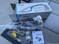 Photo showing the massager, power cord, two massage heads, instruction manual and the original box packaging.