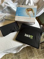 Three item lot shown: ObusForme neck massager box, and two black BackFit Clinic support pads on white cloth.