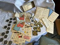 Wide view showing badges, patches, coins, awards, and paperwork spread on cloth background