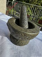 Photo showing entire stone mortar and pestle, highlighting rough granite surface and shape.