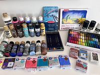 Full lot showing various brands and types of paint bottles, ink pencils, pastel set, and sealed clay packages