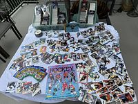 Wide view of assorted hockey trading cards spread out on a white cloth, including sticker album and loose cards.