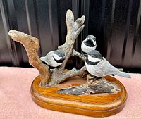 Front view of three hand carved black capped chickadees on a detailed wood mount base