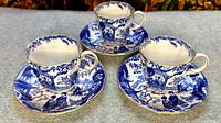 Three sets of Royal Crown Derby Mikado demitasse blue and white patterned cups with matching saucers arranged on a surface.