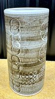 Front view of gray cylindrical vase showing incised circular and dot patterns with horizontal texture.