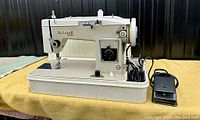 Side view of Omega Ultra sewing machine on table showing body, foot pedal and power cord.