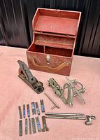 Lot overview showing Record combination plane body, Stanley plane, wooden box, cutters and rods on cloth