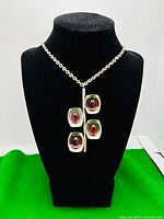 Necklace displayed on black velvet bust showing pendant's shape and glass cabochons.