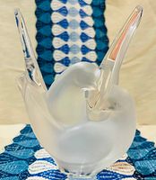 Frosted Lalique 'Sylvie' vase showing paired doves with upward clear glass wings on blue fabric background.