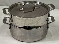 Three-piece All-Clad steamer pot set assembled, showing shiny stainless steel finish and handles.