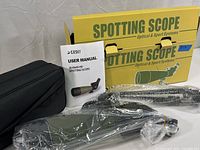 Overall view of spotting scope with packaging, manual, tripod, and carrying case before unboxing.