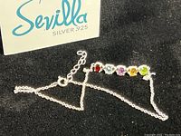 Sterling silver chain bracelet with six colorful gemstones in a horizontal row, shown on black background with Sevilla box.