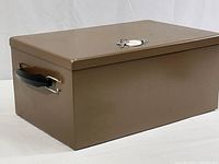 Side view of rectangular brown metal box with black plastic handle, showing overall condition and shape.