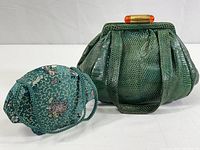 Fabric covered makeup clutch with teal floral embroidery and built-in mirror photographed alongside purse
