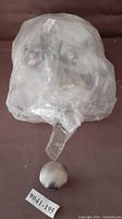 Nickel drawer knobs in a sealed plastic bag with one round knob shown outside the bag.