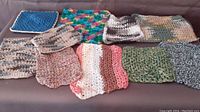 Photo of 10 crocheted dishcloths arranged on a flat surface showing various colors and patterns.