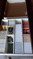 Photo of a large box divided into sections containing vertically stacked sports cards, mostly hockey cards with images of players on top.
