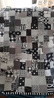 Front view of black and white patchwork quilt with various fabric patterns.