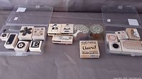 Photo showing a set of wood-mounted rubber stamps in plastic cases with floral designs, letters, and holiday themes spread out.