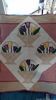 Full view of the quilted wall hanging showing the arrangement of tulip baskets and borders