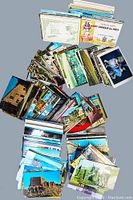 A broad view of two large stacks of assorted vintage postcards in a plastic container, showing a wide variety of images and sizes.