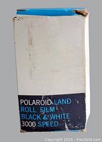 White rectangular box of Polaroid Land Roll Film with black and blue label reading 'Polaroid Land Roll Film Black & White 3000 Speed'. Some wear and discoloration visible on box edges.