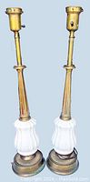 Front view of two vintage lamps with brass metal shafts and white porcelain bases, no bulbs present.