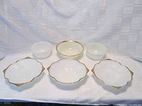 Full view of all bowls laid out showing mixing bowls in back, golden anniversary bowl in center, and grape and leaves footed and regular bowls in front