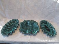Three Blue Mountain Pottery serving dishes displayed together on a white cloth backdrop. Two oval dishes and one pinwheel dish are shown.