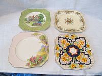 Four square plates with distinct patterns laid on white fabric background