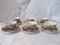 Six teacups and saucers displayed, showing transferware designs of historic Ontario scenes in brown.