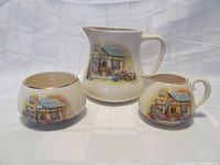Full view of the creamer, sugar bowl, and milk pitcher showing country town scene and overall set condition.