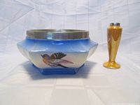 Photo of the square ESPN rimmed porcelain bowl and small amber lustreware vase side by side, showing the bird on the bowl and silver rim.