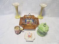 Overview photo showing all six items including two yellow lustreware vases, a brown handled plate with painted scene, green covered bowl with crown detail, oyster shell ashtray with floral pattern, and Winston Churchill Toby mug.