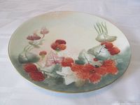 Top view of antique porcelain plate depicting strawberry vine with red berries, green leaves, white flowers, and gold trim along the edge