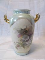 Front perspective of the Philip Rosenthal & Co Kronach porcelain vase showing multi-color floral design and gold-tone handles on a light green background.