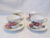 Four Ridgway Royal Vale teacups and saucers, each with a different floral pattern and gold trim, arranged together showing front views of the cups and saucers.