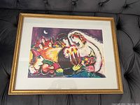 Full view of the framed art print showing the colorful romantic scene and gold frame.