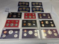 Full overview of the lot showing multiple United States Mint Proof and Presidential Coin Sets in different colored holders (black, red, purple) and blister packs arranged on a white surface.